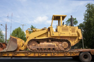 A heavy piece of construction equipment on a flat bed truck
